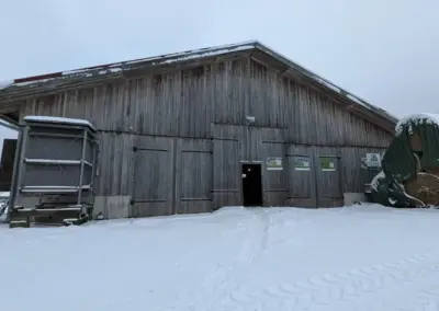 Kuhstall im Winter mit Ballenstapel neben Eingang
